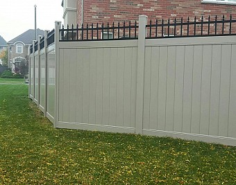 Tan, 7' high privacy fence with black metal picket top